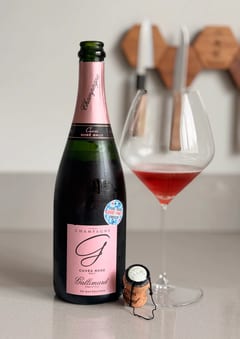 Fles Gallimard Cuvée Rosé Brut de macération met Vindeux-sticker naast een glas diep framboosrode champagne