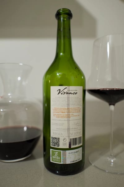Achterzijde van een fles Vivanco Rioja met karaf en glas op een lichte ondergrond
