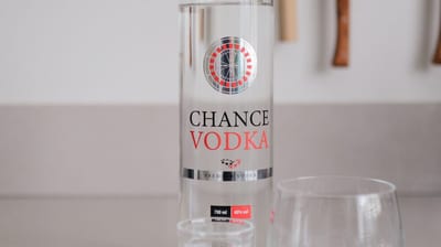 Fles Chance Vodka op een tafel met een glas op ijs ernaast