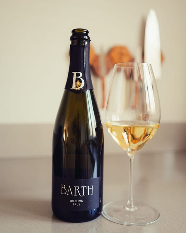 Fles Barth Riesling Brut uit de Rheingau naast een glas mousserende wijn