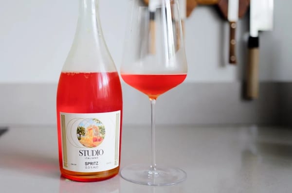 Fles Kolonne Null Spritz Studio Italiano naast een glas rosé-oranje spritz op een aanrecht